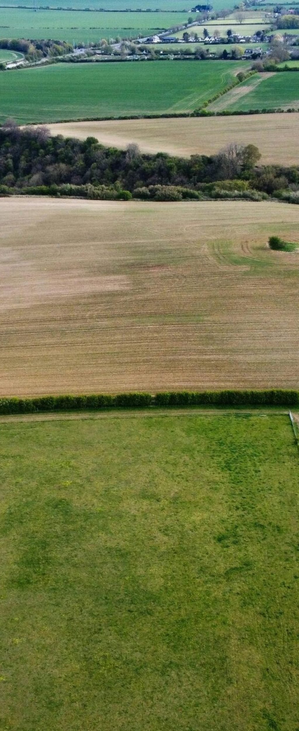 Aerial shot of lush green and brown agricultural fields in Sharpenhoe, England